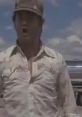 Truck driver from "Thelma & Louise" passionately expressing frustration in a dusty landscape.