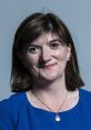 Nicky Morgan smiles in a blue dress, showcasing her signature style and role in UK politics.