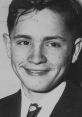 Young Charles Manson smiling in a black and white portrait, showcasing his early life before notoriety.