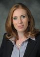 Angela Rayner with a professional hairstyle, wearing a suit, smiling confidently against a neutral background.