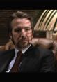 Hans Gruber, the iconic villain from Die Hard, sitting in a leather chair with intense expression and dramatic lighting.