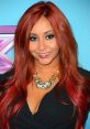 Nicole Polizzi, known as Snooki, smiles with vibrant red hair and glamorous jewelry at a formal event.