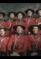 Monty Python cast in red Mountie uniforms, performing a comedic song with a backdrop of mountains. Celebrate humor and music!