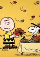 Charlie Brown serves food to Snoopy for Thanksgiving, surrounded by autumn leaves and a festive table setting.