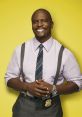 Terry Jeffords from Brooklyn Nine-Nine smiling confidently in a purple shirt with a badge and suspenders against a yellow backdrop.