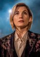 Jodie Whittaker as the Doctor in Doctor Who, gazing upwards with a thoughtful expression against a dramatic background.