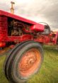 Close-up of a vintage red tractor showcasing its powerful tire and hydraulic machinery, highlighting agricultural efficiency.