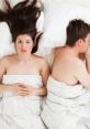 Couple in bed with contrasting emotions; intimacy and distance represented by their body language and posture.