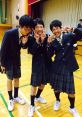 Three male students in skirts pose playfully in a school gym, showcasing Japanese school culture with vibrant energy.