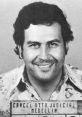 Pablo Escobar's mugshot from the Medellín prison, showing his charismatic smile and distinctive floral shirt.