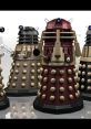 Four iconic Daleks from Doctor Who, showcasing their distinctive shapes and colors in a science fiction setting.