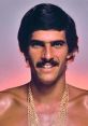 Portrait of a smiling man with a thick mustache and gold chains, showcasing 70s fashion and style.