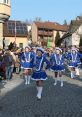 Women in blue costumes march cheerfully during a vibrant German Carnival parade, celebrating tradition and festivity.