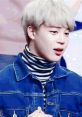 Jimin from BTS wearing a denim jacket and striped turtleneck, expressing excitement during a performance.