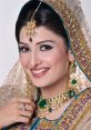 Elegant Pakistani woman wearing traditional jewelry and attire, featuring intricate designs with emerald accents and vibrant colors.