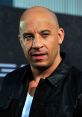 Vin Diesel in a black leather jacket, showcasing his signature bald look and intense expression at a red carpet event.