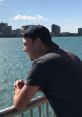 Young man enjoying a scenic view of the waterfront with city skyline, ideal for relaxation and inspiration.