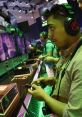 Gamer focused on gameplay at an event, using a controller and wearing headphones, surrounded by fellow gamers.