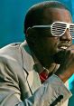 Kanye West performs passionately, wearing iconic sunglasses and a stylish suit, showcasing his unique artistry.