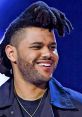 The Weeknd smiles brightly with unique hairstyle, showcasing his charismatic presence in a stylish outfit.