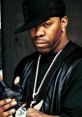 Busta Rhymes posing confidently in stylish attire, showcasing his iconic look and distinctive hip-hop style.