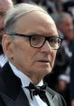 Ennio Morricone in a tuxedo, showcasing his iconic style at a prestigious event, embodying musical genius and elegance.