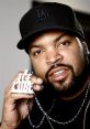 Ice Cube showcasing his signature jewelry, wearing a black LA cap, exuding charisma and confidence in a close-up shot.