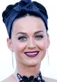 Katy Perry showcases a stunning look with bold makeup and a stylish headwrap at a red carpet event.