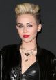 Miley Cyrus showcases a bold look with a stylish blonde pompadour and striking red lips, exuding confidence and glamour.