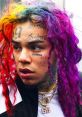 Tekashi 6ix9ine showing off vibrant, multi-colored hair and distinctive tattoos during a public appearance.