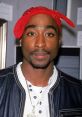 Tupac Shakur with a red bandana and leather jacket, showcasing his iconic style and influence in hip-hop culture.