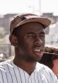 Tyler the Creator wearing a Supreme cap and a pinstriped jersey, showing his unique street style at a sunny event.