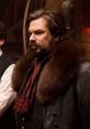 Character from "What We Do in the Shadows" with a dramatic fur collar and ornate attire, exuding a classic vampire vibe.