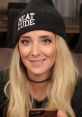 Jenna Marbles smiles while wearing a "Neat Dude" beanie, holding a phone, showcasing her fun personality.