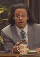 Eric Andre animatedly discussing themes with a snack in hand on set, showcasing the show's quirky humor and style.