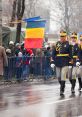 Romanian soldiers march in a parade, showcasing national pride with the Romanian flag in a festive atmosphere.