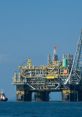 Oil rig structure in open water with a tugboat nearby, showcasing offshore oil extraction and energy resources.