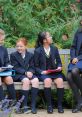 Girls in blazers and skirts sitting on a bench, enjoying a conversation in a lush garden at a Girls’ Grammar School.