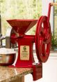 Red GrainMaker mill on a kitchen counter with flour and an elegant design, perfect for home milling grains and baking.