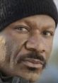 Close-up of an irate Black man wearing a black beanie, displaying a serious expression and intense gaze.