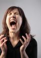 Woman with long dark hair screaming in frustration, hands raised, expressing intense emotion in a dramatic pose.