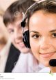 Smiling phone operator in headset, providing customer support with team members in the background, showcasing effective communication.