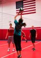 Player jumping to set a volleyball during practice, showcasing teamwork and skill in a vibrant indoor gym.