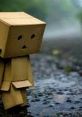 Sad cardboard character standing alone on a wet road, evoking feelings of loneliness and melancholy inspired by Sad FX.