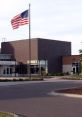 Modern school building with an American flag, featuring a welcoming entrance and landscaped surroundings.