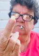 Confident older woman in glasses showing middle finger while holding a cigarette, conveying bold attitude and defiance.