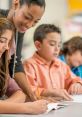 Teacher guiding students in a classroom as they engage in writing activities, fostering collaborative learning.