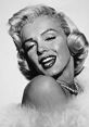 Classic portrait of Marilyn Monroe smiling, featuring her iconic platinum blonde hair and elegant fur wrap.