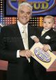 John O'Hurley and baby Dylan pose with a "Family Feud" sign, showcasing a heartwarming moment on the popular game show.