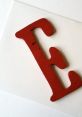 Red wooden letter "E" displayed on a white background, perfect for educational materials or decorative ideas.